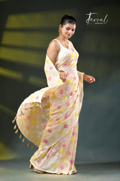 A woman modeling a light beige or cream saree with pink and yellow floral motifs, paired with a white sleeveless blouse. The image is set against a dark gray background with a soft spotlight effect and a 'Farral' brand watermark in the upper right corner.
