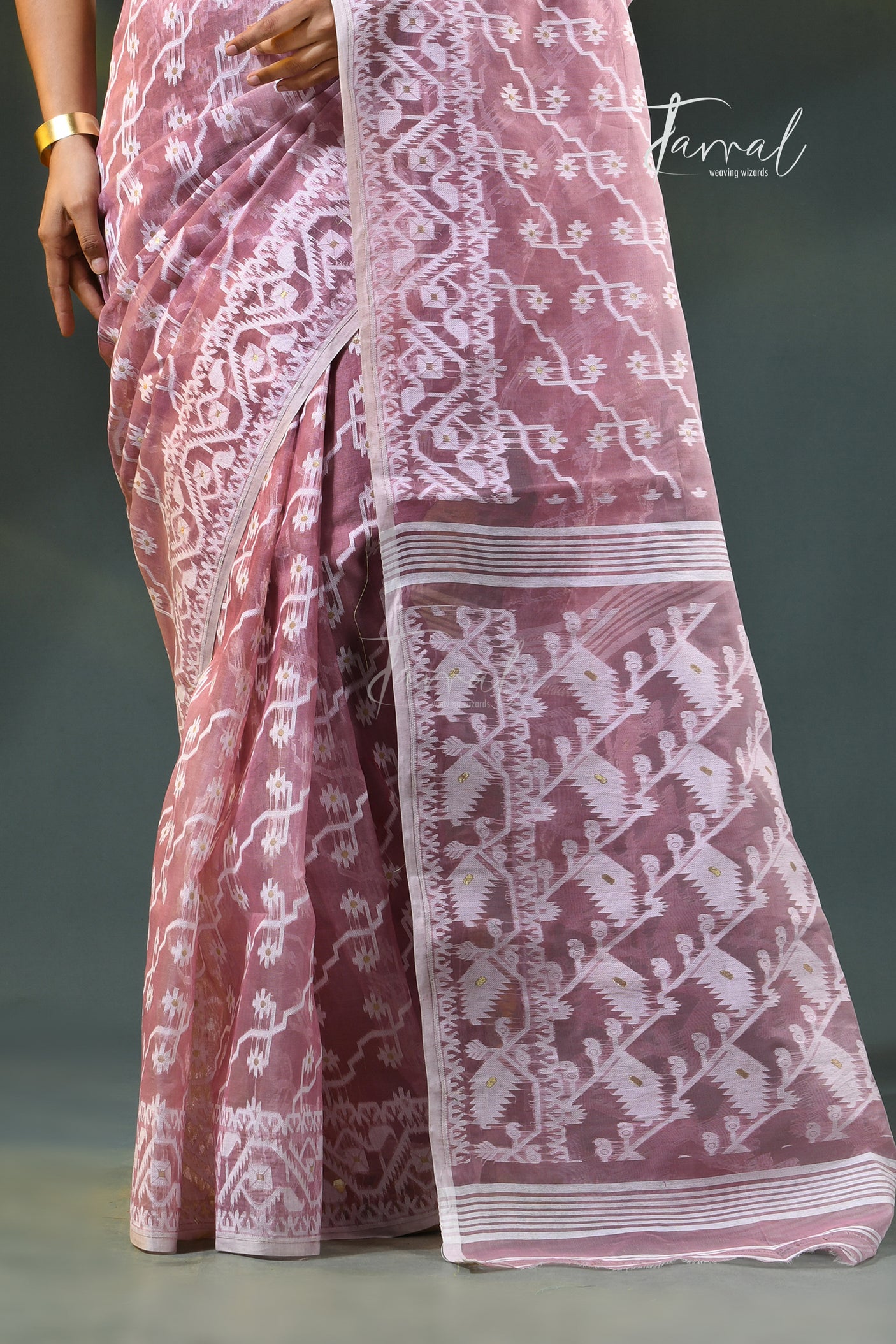 A woman modeling a onion pink and white patterned saree with a white blouse, accessorized with gold earrings, against a dark green gradient background. The brand name 'Farral' is visible in the top right corner.
