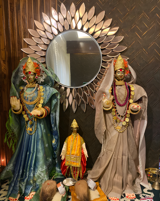 Two statues in traditional attire with a decorative mirror in the center.
