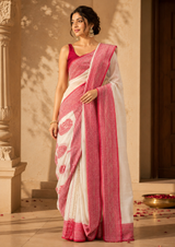 Woman wearing a white and pink saree in an indoor setting