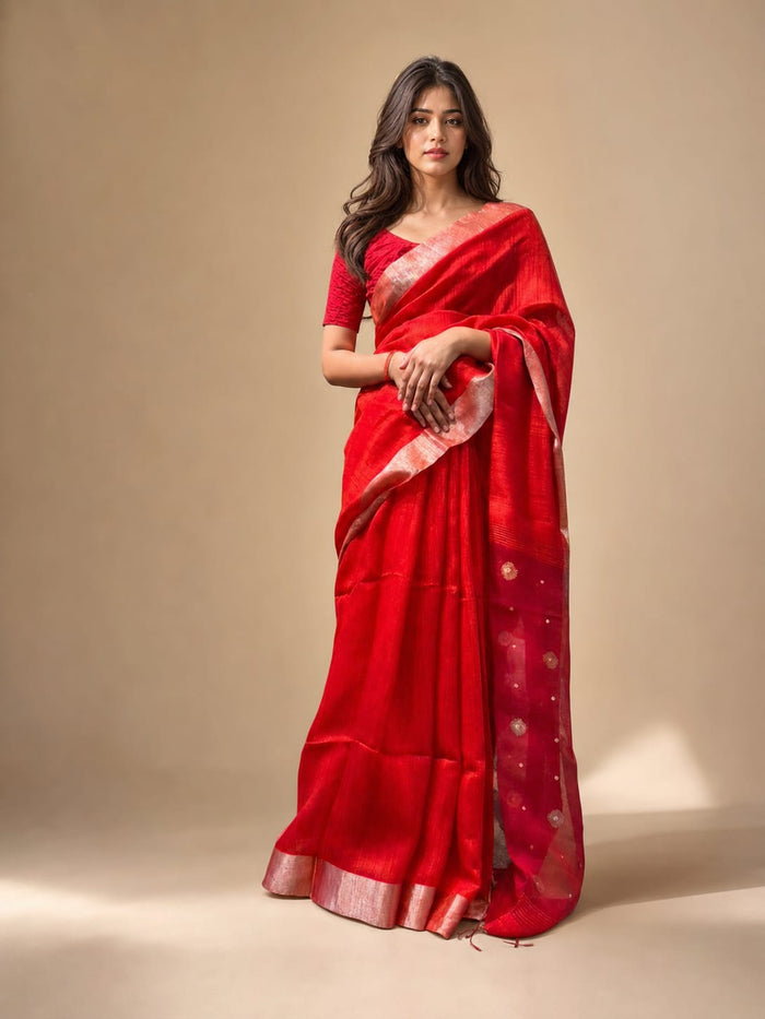 Woman wearing a red saree with gold border on a beige background