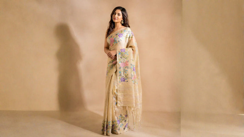 Woman in a floral saree standing against a beige background